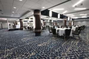 Kalamazoo Room - Event Space - Large room with wooden pillars. Round banquet tables with white linens, chairs surrounding each table